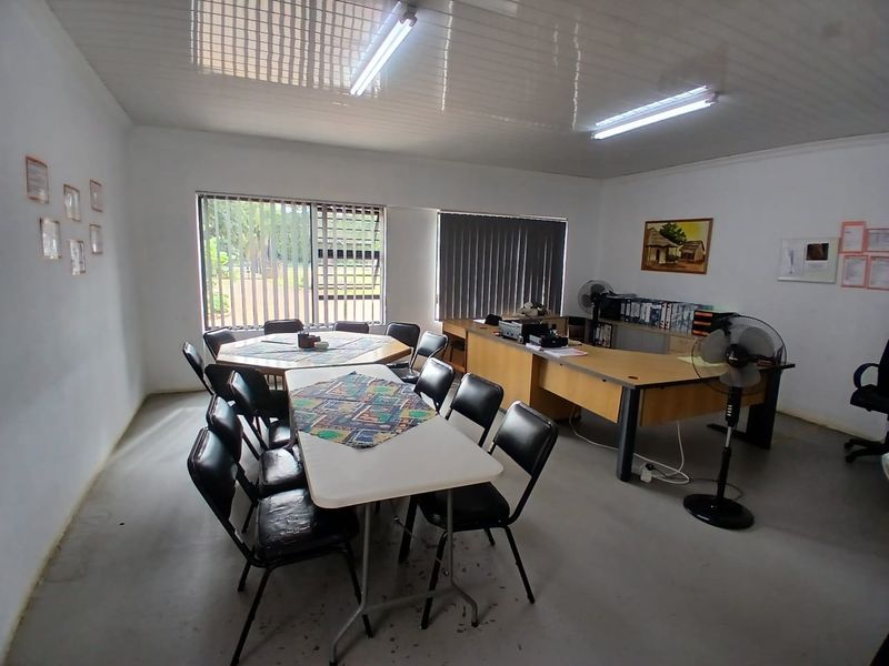 A functional office space featuring louvered windows, vertical blinds, and overhead fluorescent lighting, suitable for a home-based business or administrative area.