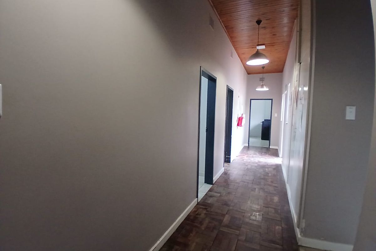 A spacious hallway featuring warm parquet flooring and a classic wooden tongue and groove ceiling, providing access to multiple rooms.