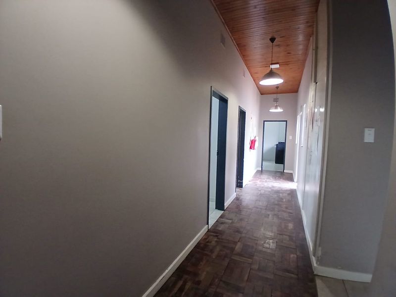 A spacious hallway featuring warm parquet flooring and a classic wooden tongue and groove ceiling, providing access to multiple rooms.