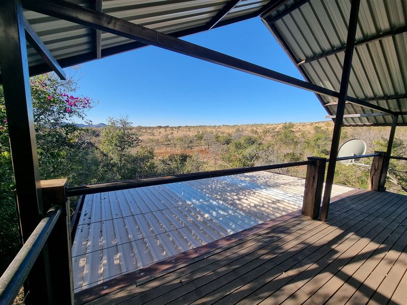 An elevated timber balcony featuring a metal roof structure and open views of the surrounding natural landscape.