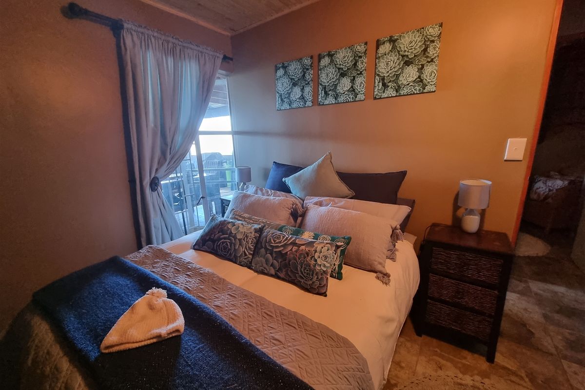 A cozy bedroom featuring a timber-clad ceiling, tiled flooring, and a sliding glass door providing access to an outdoor area.