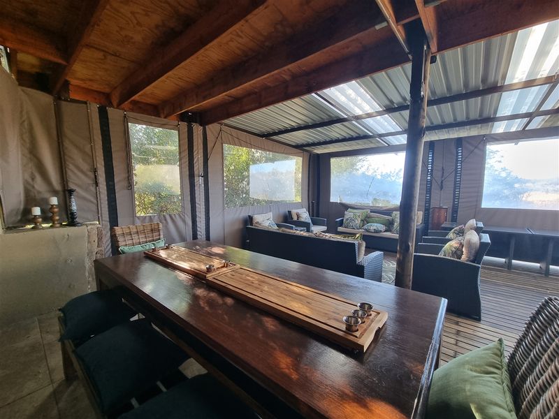 Covered outdoor patio area featuring timber decking, exposed rafters, and roll-up canvas walls, providing a versatile space for outdoor dining and relaxation.