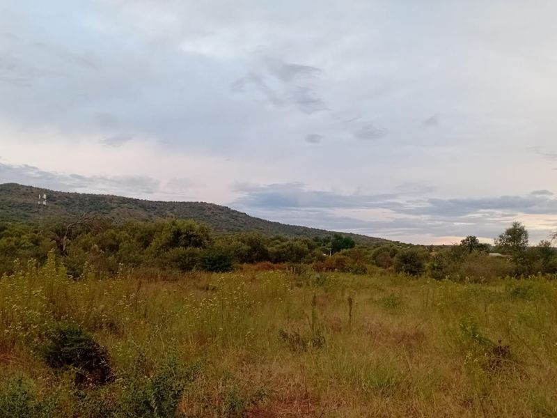 A scenic view of the vacant residential land featuring natural vegetation and rolling hills in the background.