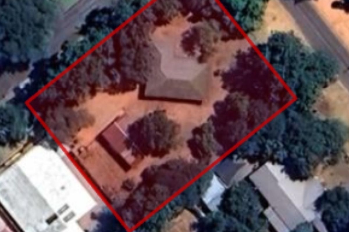 Aerial view of the property site showing the building footprint and surrounding grounds within the highlighted boundary.