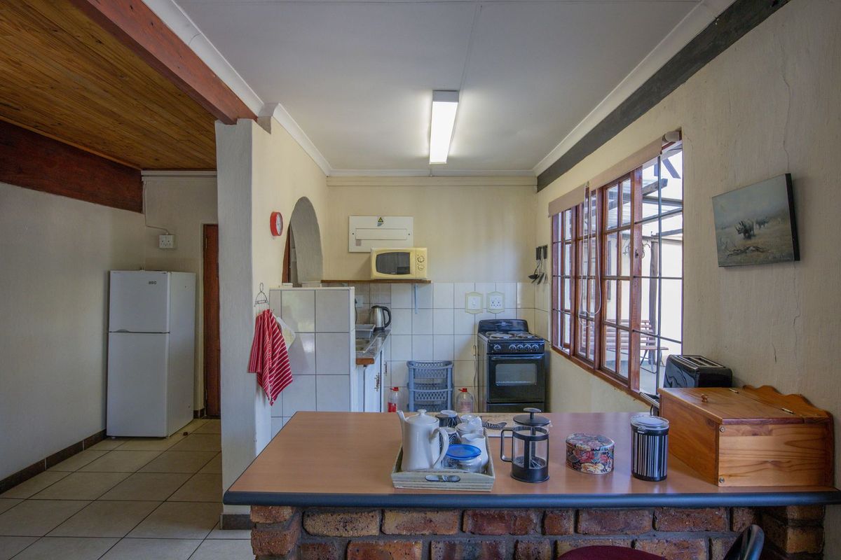 Functional kitchen featuring a brick breakfast counter, tiled splashback, and timber window frames, offering a rustic aesthetic with potential for modern updates.