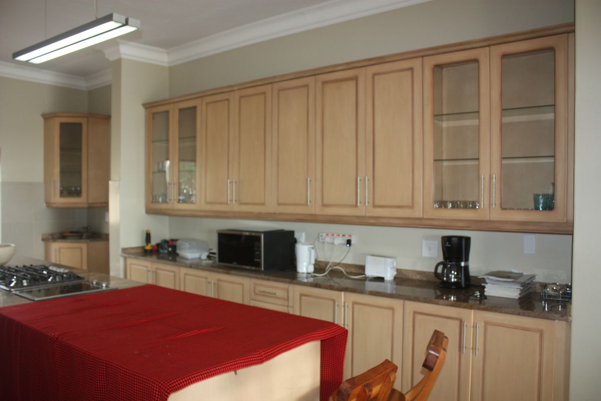 Spacious kitchen featuring light wood cabinetry, granite countertops, and a central island with a built-in gas hob.