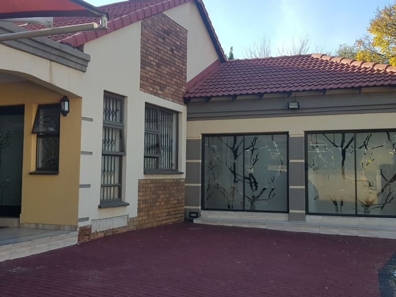 Front elevation of a residential house featuring a paved driveway, covered entrance, and large sliding glass doors with decorative frosted film.