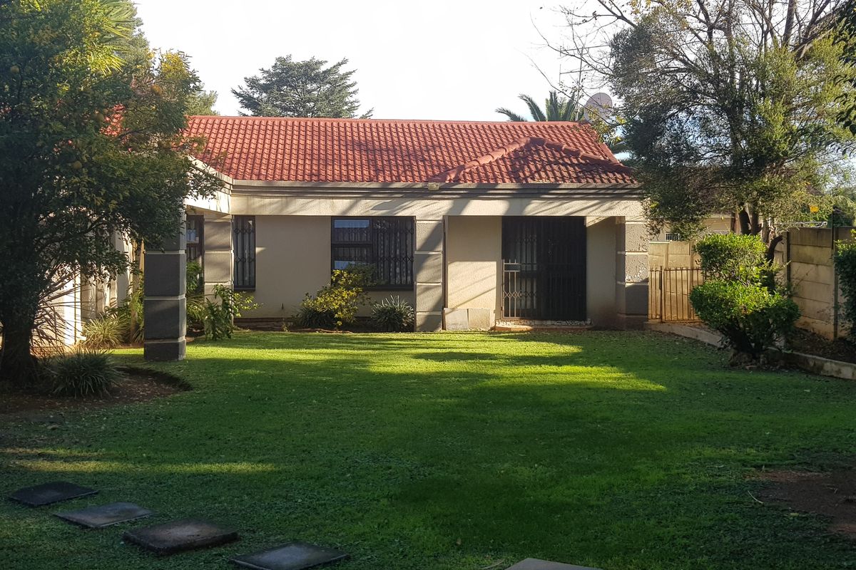 A view of the rear elevation of the house featuring a tiled roof, security-fitted windows and doors, and a well-maintained garden area.