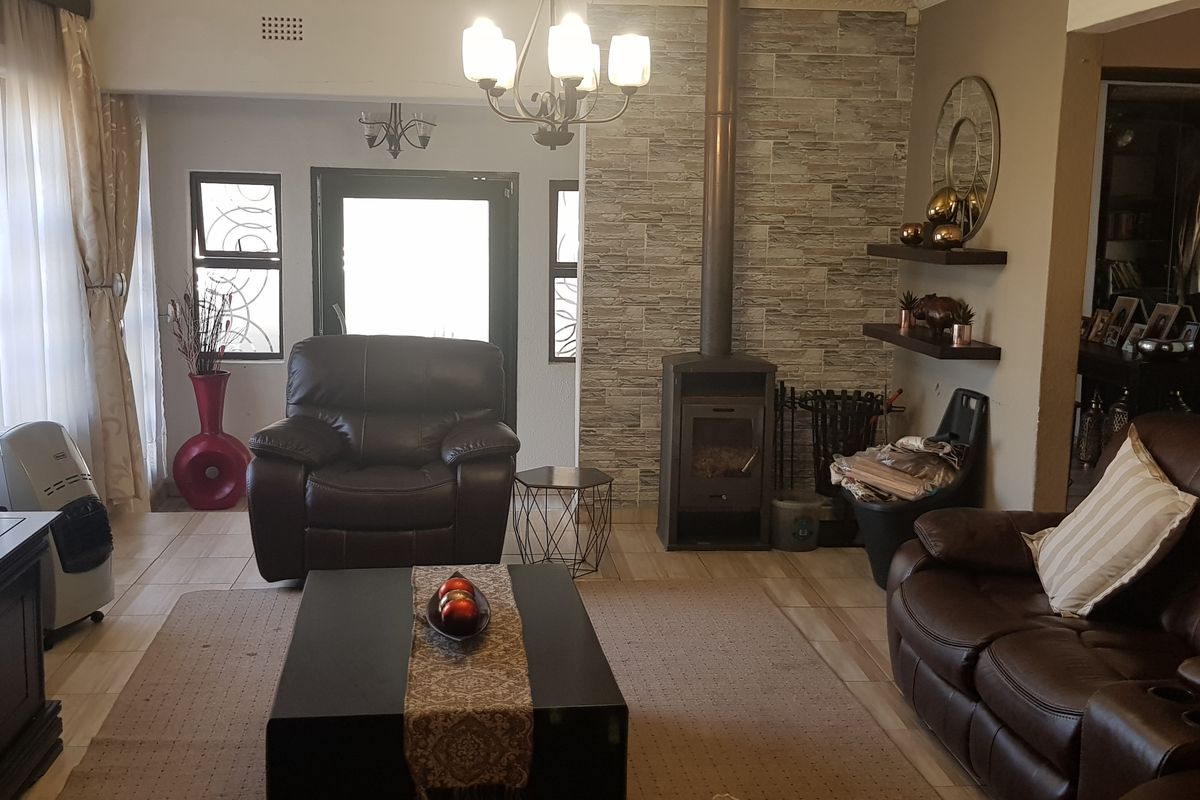 A comfortable living room featuring a stone-clad feature wall with a built-in fireplace, tiled flooring, and natural light from the entrance.