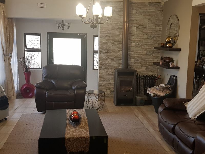 A comfortable living room featuring a stone-clad feature wall with a built-in fireplace, tiled flooring, and natural light from the entrance.