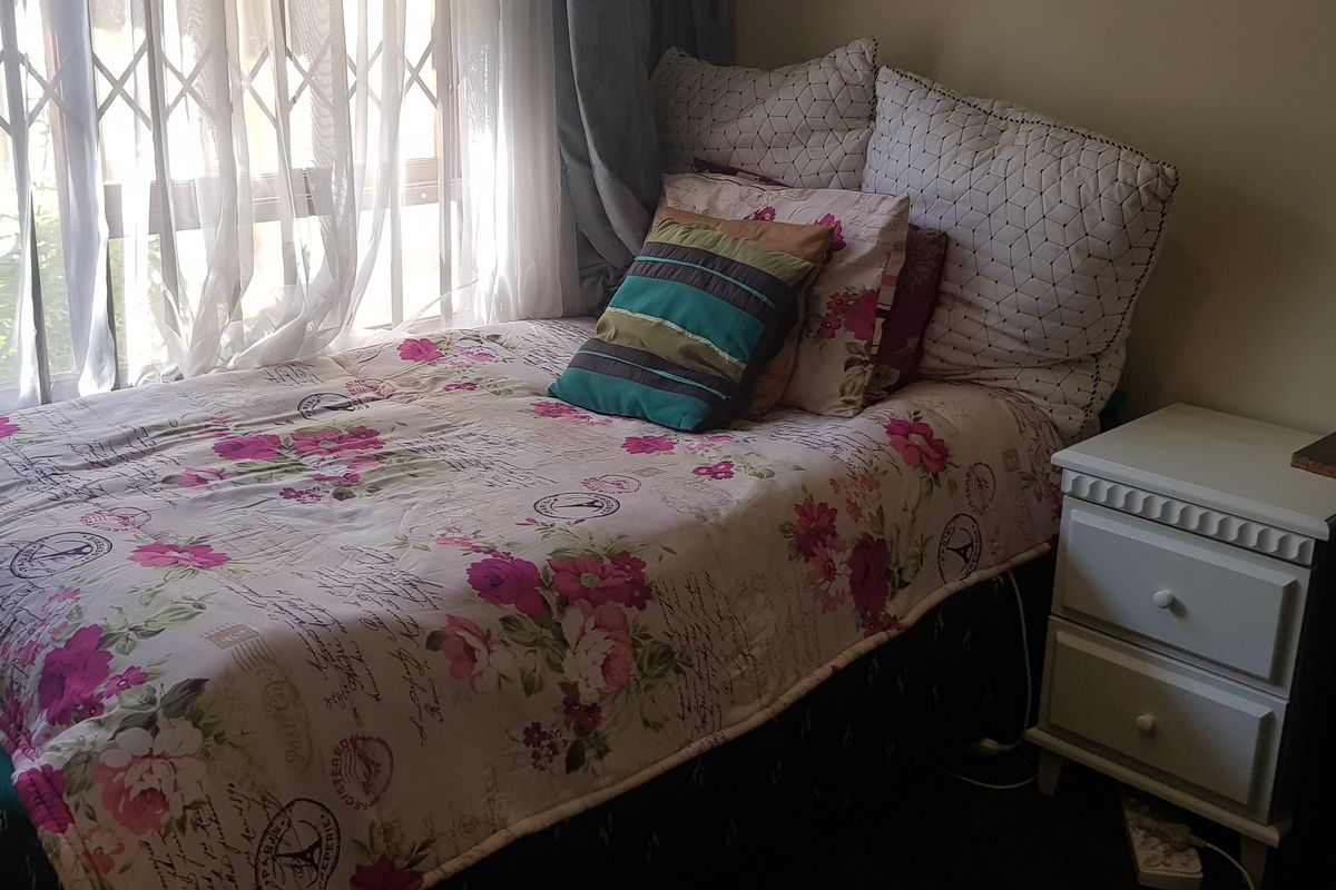 A bedroom featuring a window with a fitted security gate, providing natural light and ventilation.