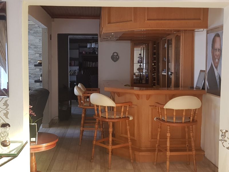 A dedicated bar area featuring a built-in wooden counter, cabinetry, and tiled flooring, providing a functional space for entertaining.