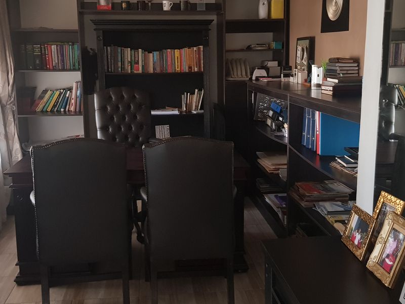 A home office space featuring built-in shelving units and tiled flooring, providing a functional workspace with ample storage.