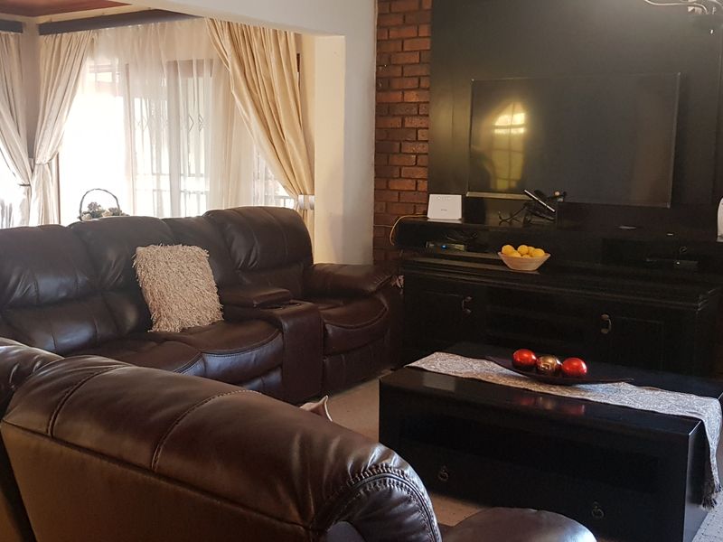 A comfortable living room featuring an exposed brick accent wall, tiled flooring, and large sliding doors that provide access to the outdoor area.