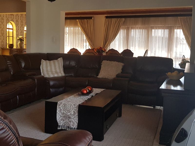 A spacious living room featuring tiled flooring, large windows with natural light, and an architectural archway leading to an adjacent area.