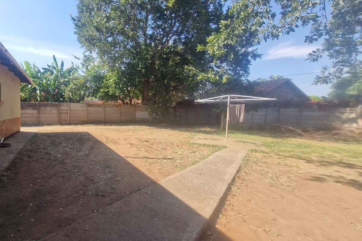 A spacious rear garden featuring a concrete pathway, precast boundary walling, and a rotary clothesline, offering potential for landscaping and outdoor improvement.