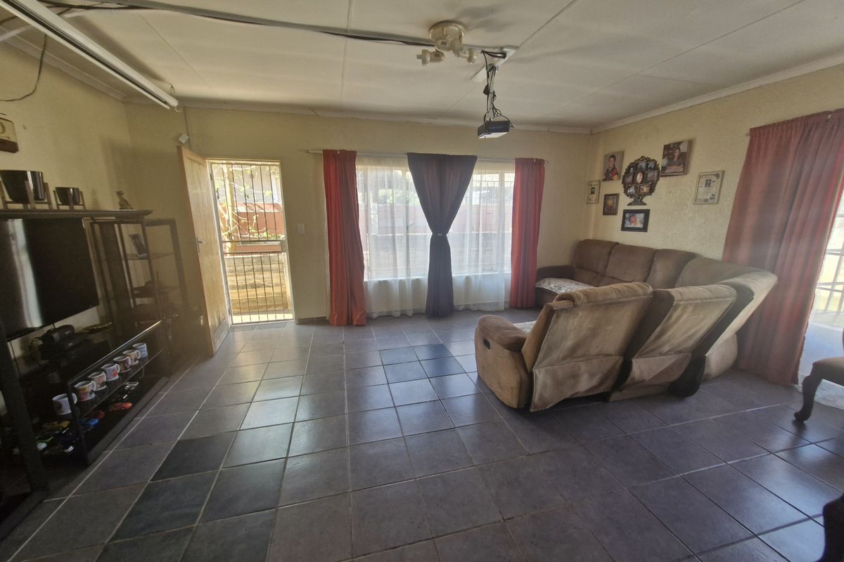 A spacious living room featuring tiled flooring, a security gate at the entrance, and a ceiling-mounted projector, offering a functional and comfortable living space.