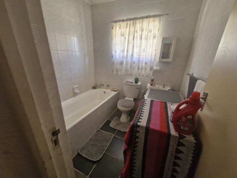 A functional bathroom featuring a bathtub, toilet, and washbasin with tiled wall and floor finishes.
