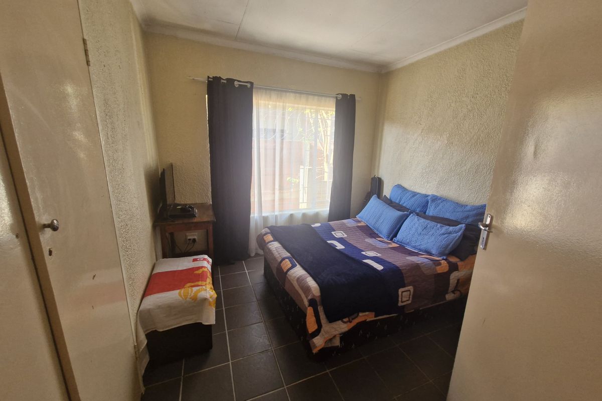 A compact bedroom featuring tiled flooring and a built-in cupboard, requiring cosmetic updates to the wall finishes and ceiling.