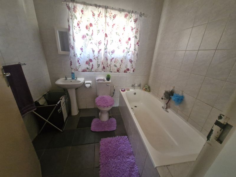 A functional bathroom featuring a pedestal basin, toilet, and a built-in bathtub with full-height wall tiling.