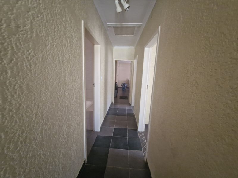A functional hallway featuring tiled flooring and textured wall finishes, providing access to multiple rooms within the property.