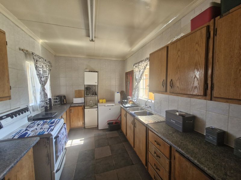 A functional kitchen featuring wooden cabinetry, tiled splashbacks, and a double bowl stainless steel sink, offering potential for a modern renovation.