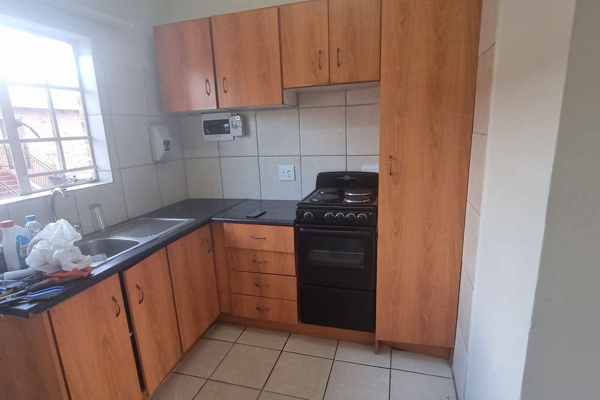 A functional kitchen featuring laminate cabinetry, a stainless steel sink, ceramic tile backsplash, and a freestanding stove with ample storage space.