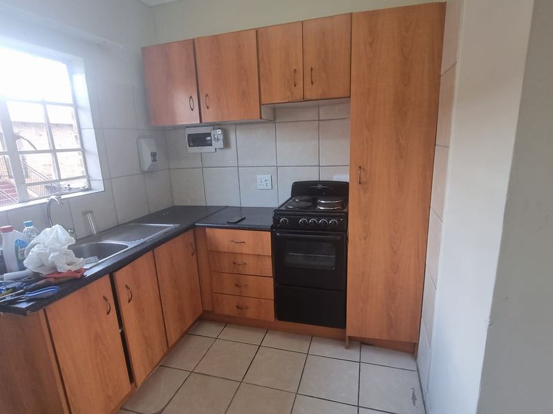 A functional kitchen featuring laminate cabinetry, a stainless steel sink, ceramic tile backsplash, and a freestanding stove with ample storage space.
