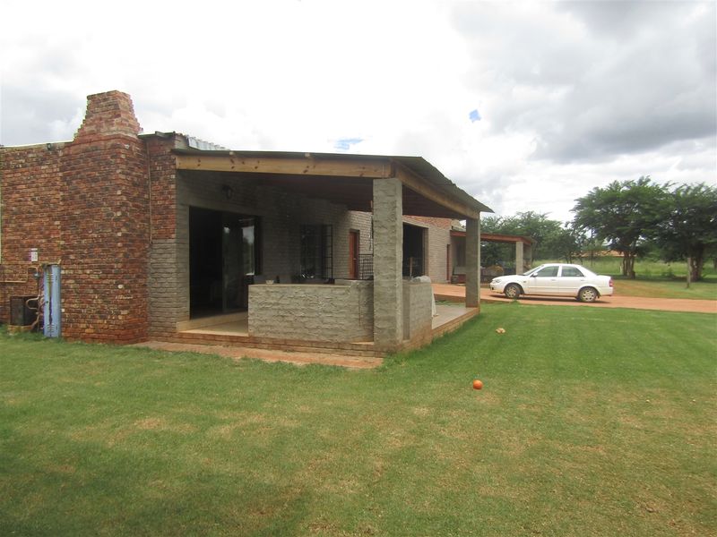 Rear view of the property featuring a covered patio area, brick chimney, and sliding door access to the interior.
