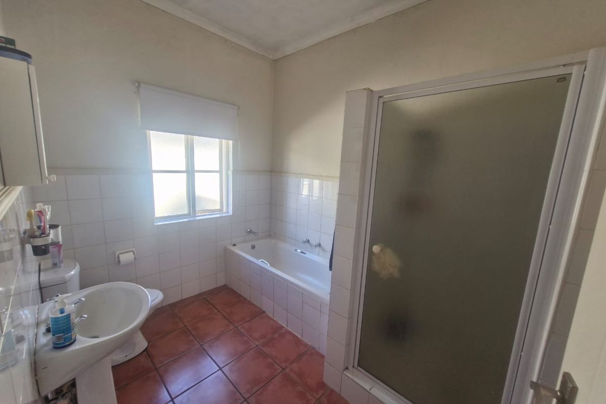 A functional bathroom featuring a pedestal basin, built-in bathtub, and a separate shower enclosure with tiled finishes.