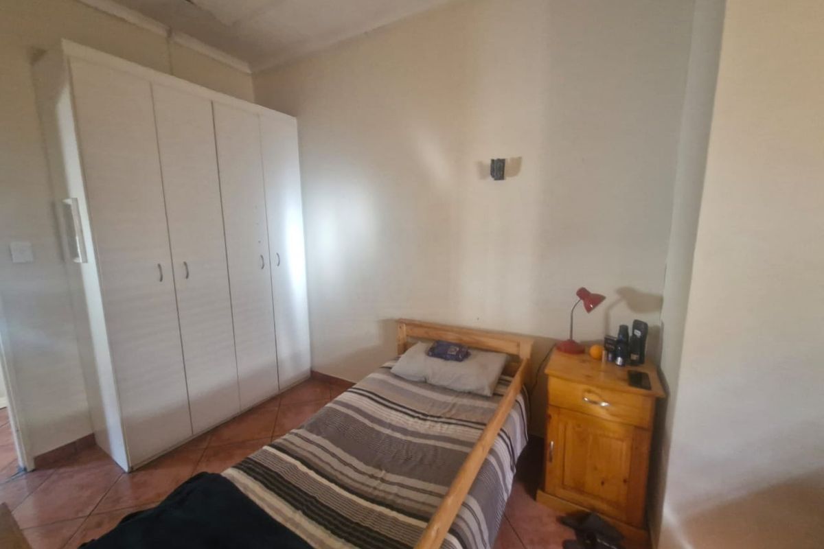 A functional bedroom featuring tiled flooring and a built-in wardrobe, providing essential storage space.