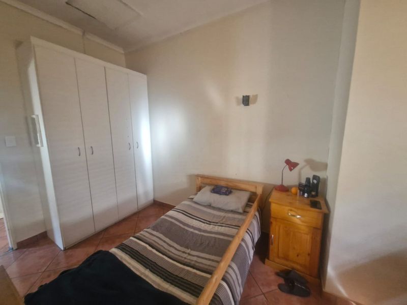 A functional bedroom featuring tiled flooring and a built-in wardrobe, providing essential storage space.