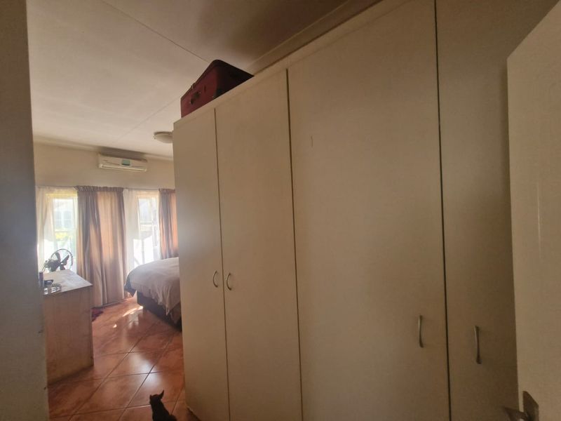 Bedroom featuring built-in cupboards, tiled flooring, and a wall-mounted air conditioning unit.