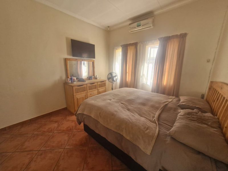 A bedroom featuring tiled flooring, a coved ceiling, and a wall-mounted split-system air conditioner.
