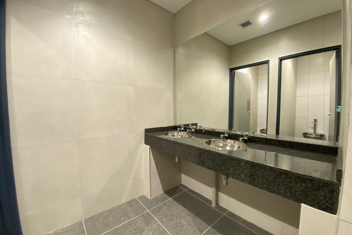 Modern industrial-style bathroom featuring a dual-basin vanity with granite countertop, stainless steel sinks, and large wall-mounted mirror.