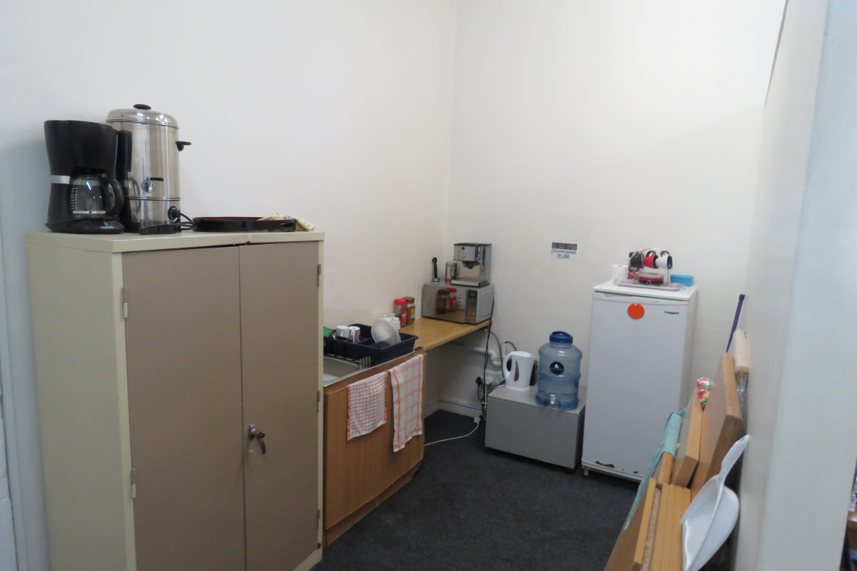 A small office kitchenette area featuring basic cabinetry, a sink, and space for small appliances, suitable for staff refreshment needs.