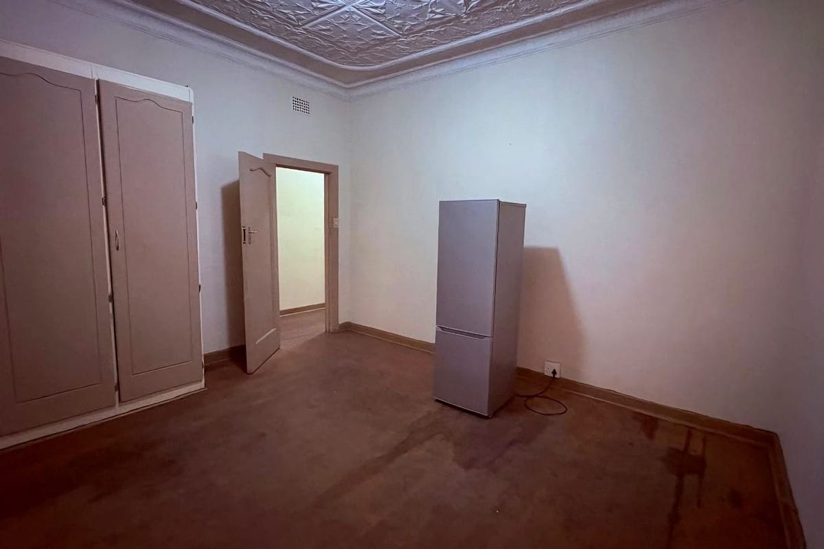 A bedroom featuring built-in cabinetry, decorative ceiling molding, and worn flooring, offering a blank canvas for renovation.