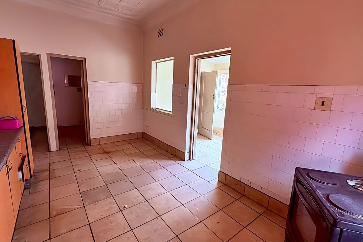 A functional kitchen area featuring tiled flooring, wall tiling, and built-in cabinetry, providing a practical workspace for industrial or utility use.