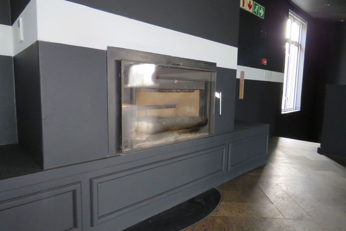A modern interior space featuring a built-in glass-fronted fireplace with dark paneling and hardwood flooring.