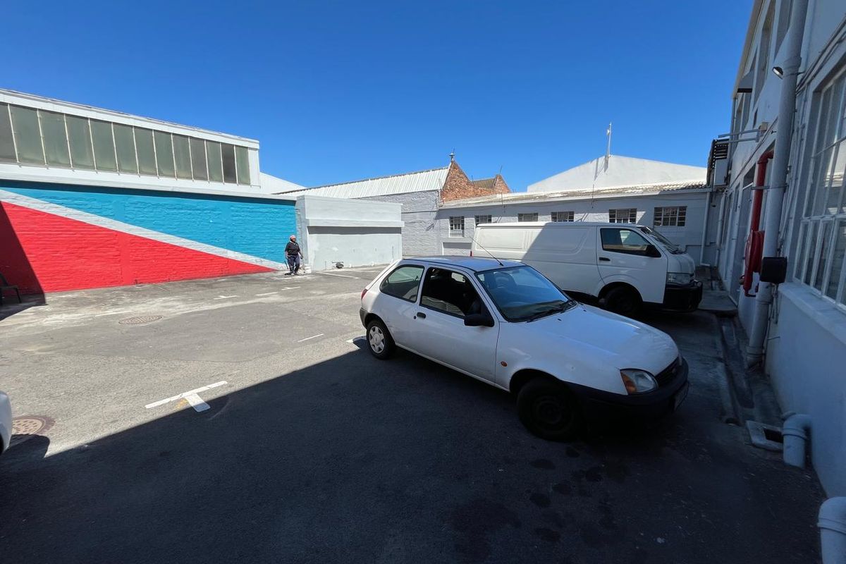 Exterior view of an industrial property courtyard featuring paved parking area and painted brick walls.