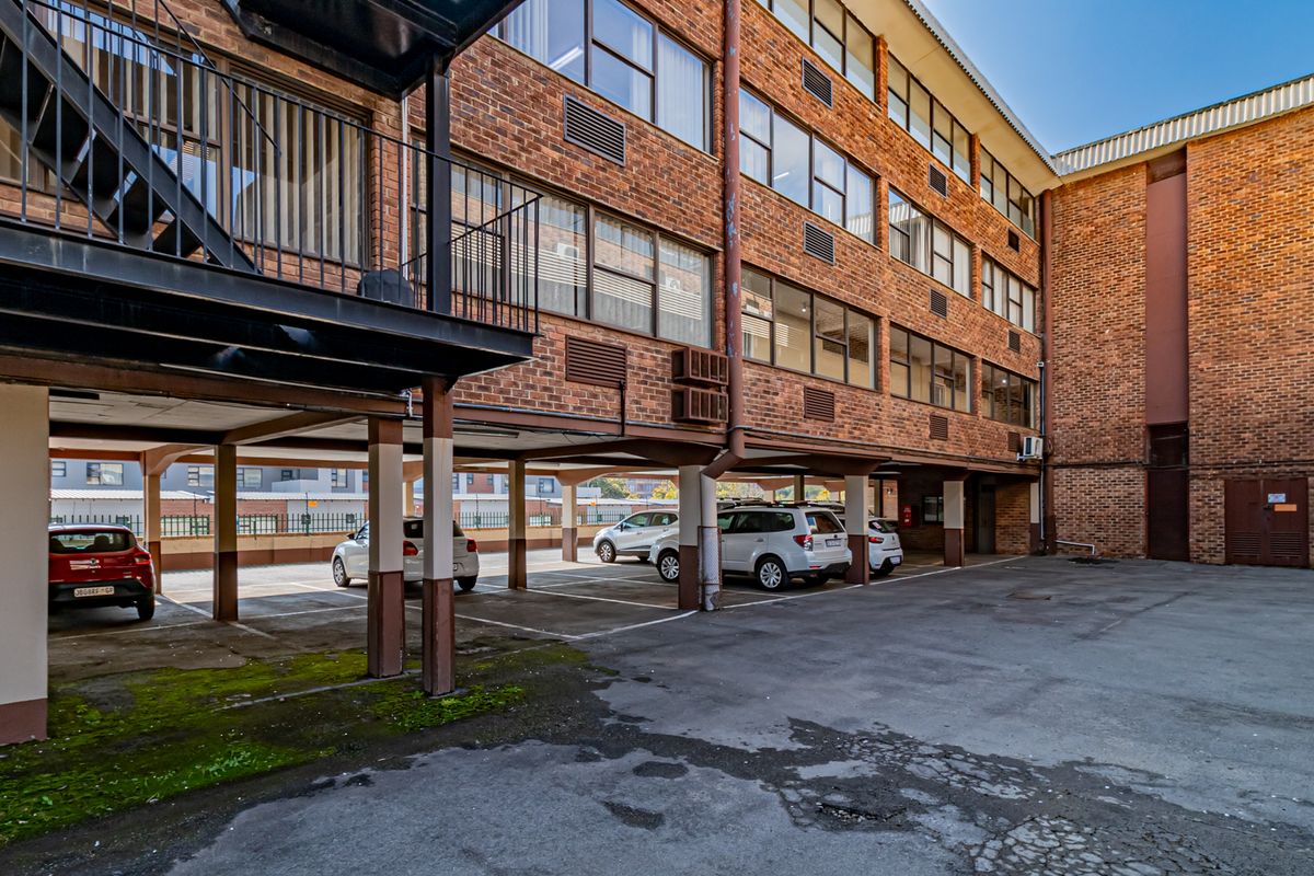 Exterior view of a multi-story brick office building featuring a covered parking area and external metal staircase access.