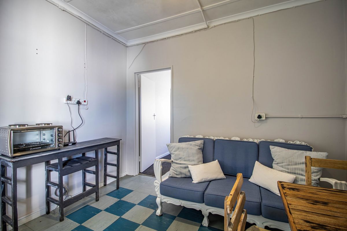 A functional interior space featuring a checkerboard floor, exposed electrical conduit, and a doorway leading to an adjacent room.