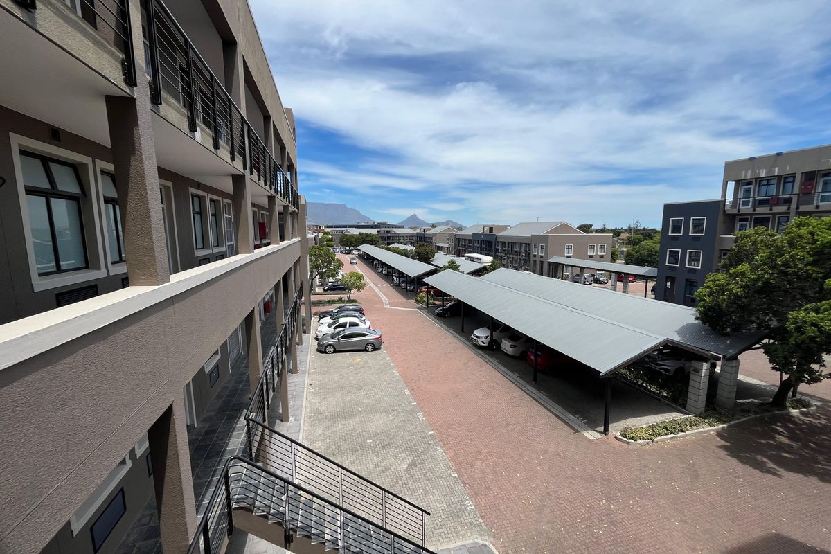 Elevated view of the office complex exterior, featuring paved parking areas, covered carports, and modern multi-story building facades.