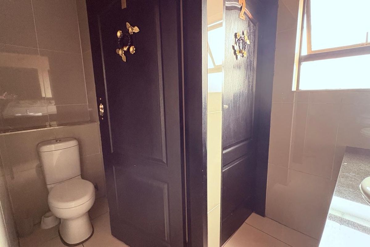 A functional bathroom featuring tiled walls, a standard toilet, and a built-in vanity basin with natural light from a window.