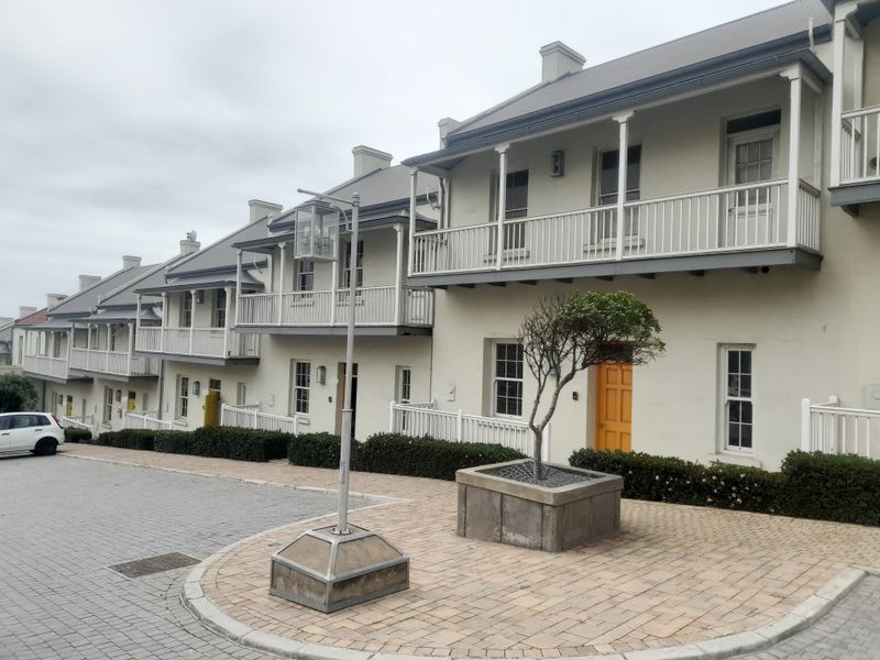 A view of a row of multi-story office units featuring classic architectural design, balconies with railings, and paved exterior walkways.