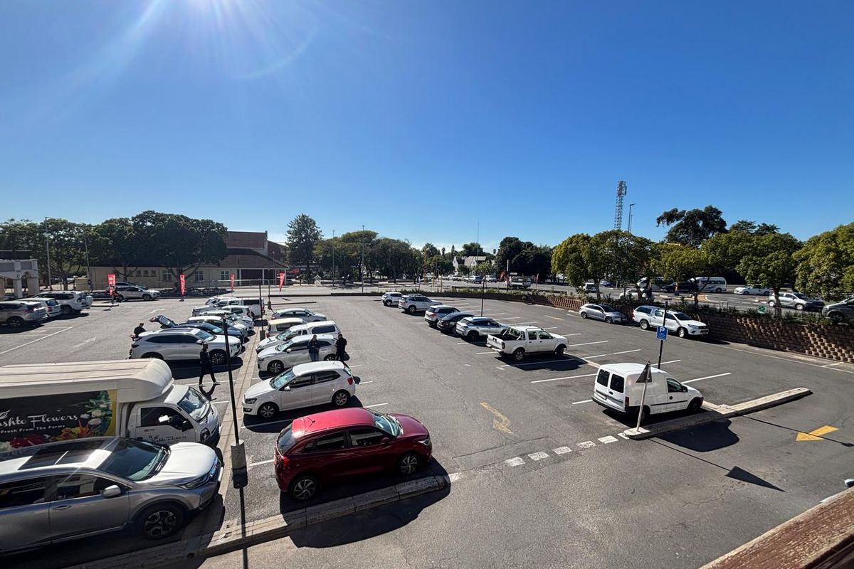 An elevated view of a paved outdoor parking area with marked bays, serving the retail property.
