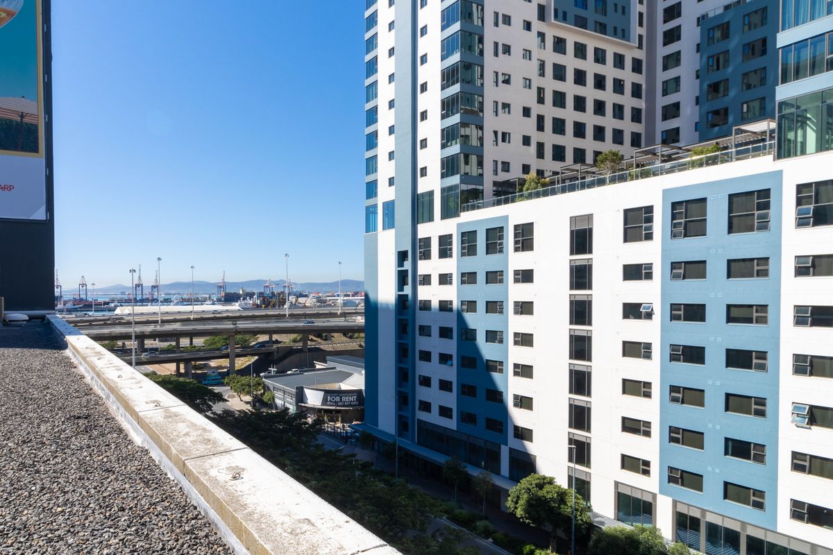 Elevated view of a modern commercial high-rise building facade with surrounding urban infrastructure and highway access.