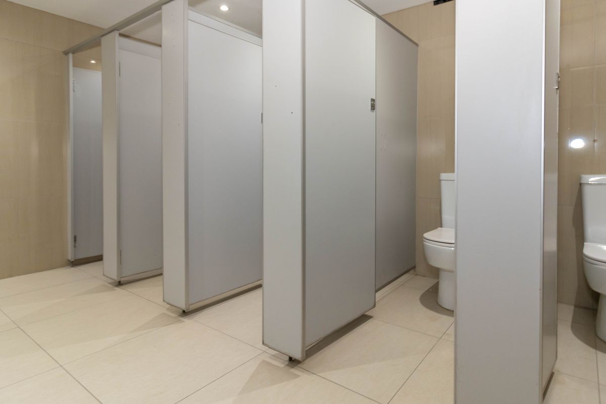 Commercial restroom facility featuring multiple partitioned toilet stalls with tiled flooring and wall finishes.
