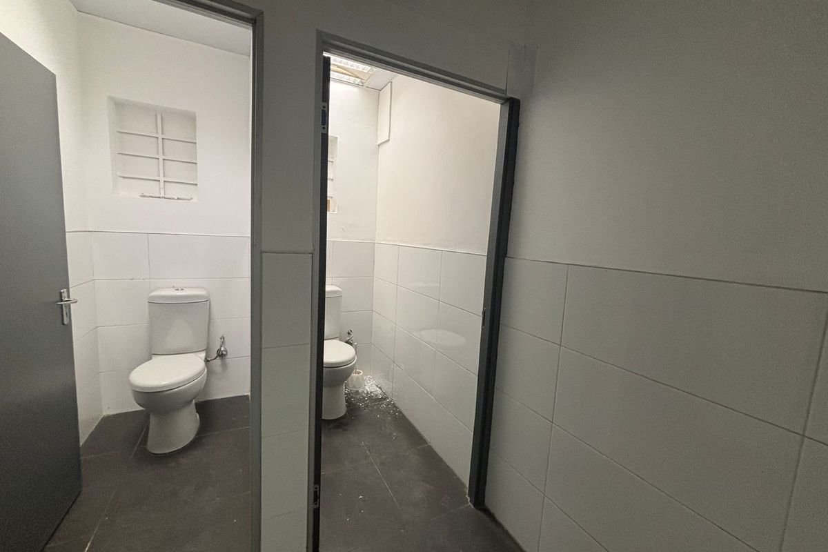 Two separate restroom cubicles featuring tiled flooring, white wall tiles, and standard porcelain toilets.