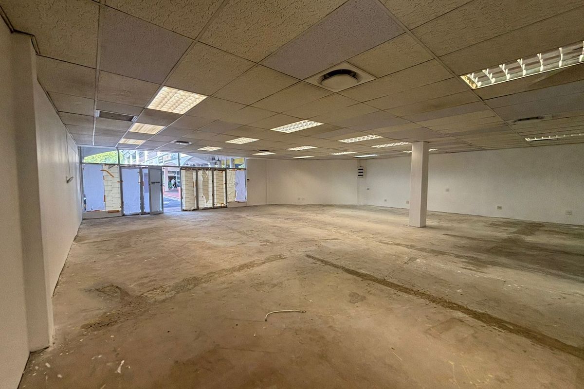 A vacant open-plan retail space featuring a suspended ceiling, recessed lighting, and concrete flooring, ready for custom fit-out.